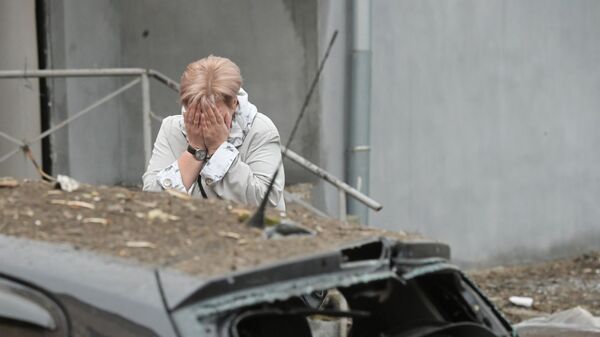 Жительница во дворе жилого дома, подвергшегося обстрелу, в Киевском районе Донецка