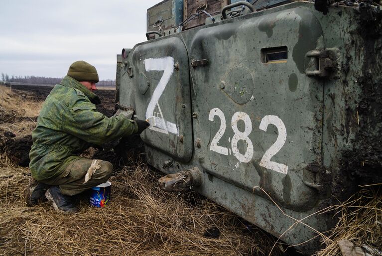 Военнослужащий народной милиции ДНР наносит знак Z на бронетехнику под Волновахой