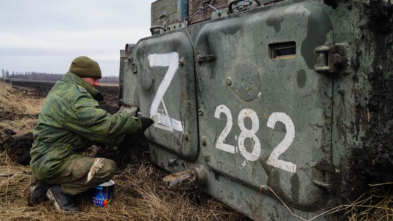 Военнослужащий народной милиции ДНР наносит знак Z на бронетехнику под Волновахой