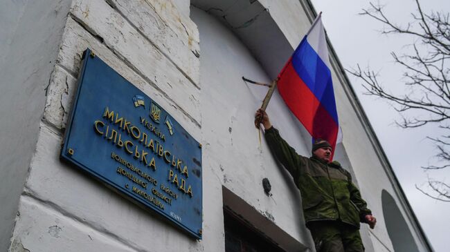 Военнослужащие Народной милиции ДНР и ВС Российской Федерации водружают флаги России и Донецкой народной республики на здании администрации села Николаевка