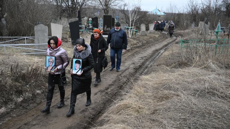 Женщины несут фотографии погибших при обстреле украинскими войсками здания школы в Горловке в ДНР