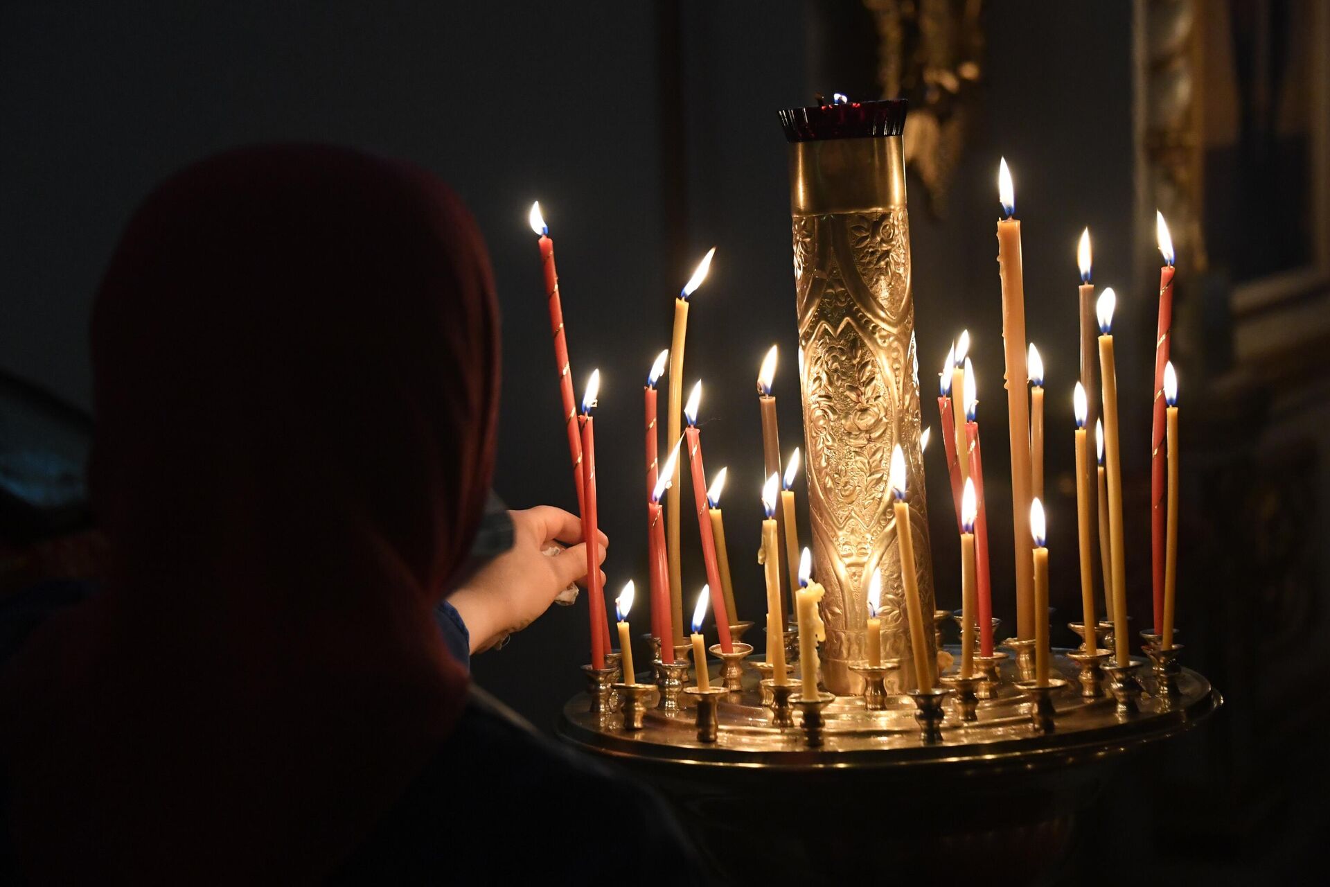 Верующая ставит свечу в храме Успения Божией Матери во Владивостоке  - РИА Новости, 1920, 12.02.2025