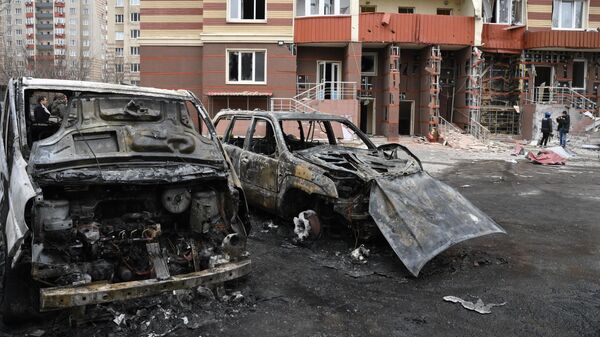 Сгоревшие автомобили во дворе многоэтажного жилого дома в Донецке, поврежденного в результате обстрела