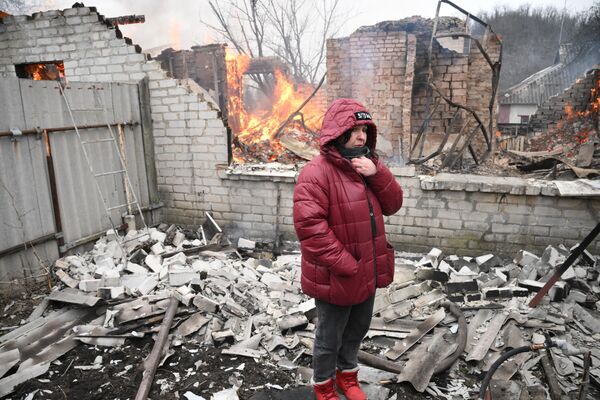 Женщина у жилого дома в Киевском районе Донецка, разрушенном в результате обстрела