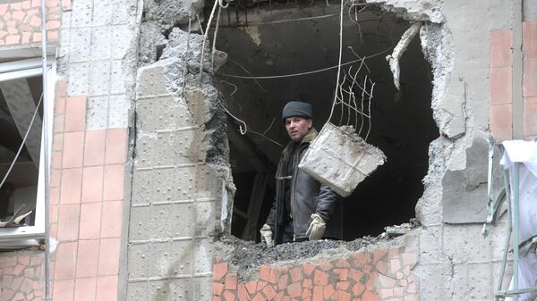 Мужчина разбирает завалы, образовавшиеся в результате попадания снаряда в дом в Горловке