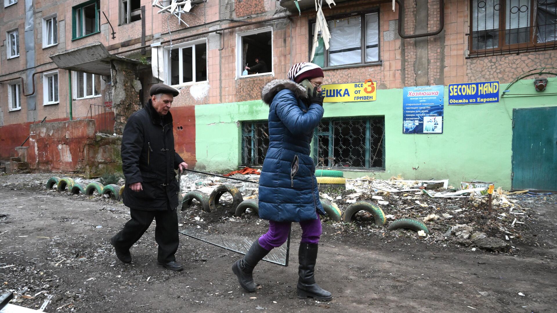 Люди идут вдоль дома, пострадавшего в результате обстрелов Горловки - РИА Новости, 1920, 02.03.2022