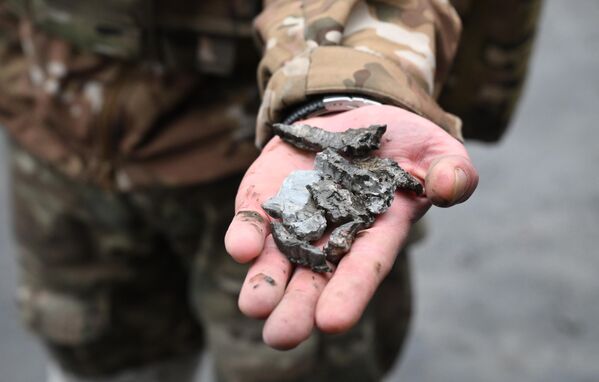 Военнослужащий демонстрирует осколки боеприпасов во дворе многоэтажного жилого дома в Донецке, поврежденного в результате обстрела