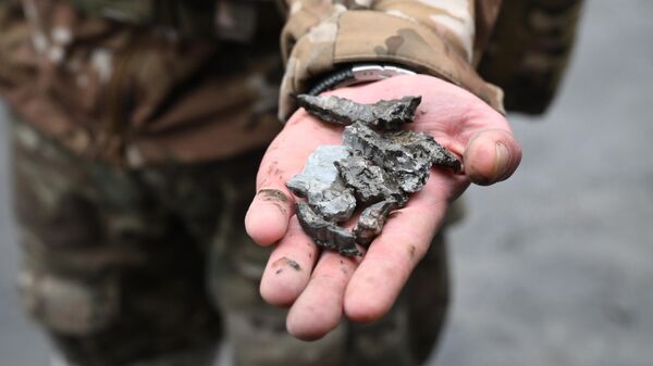 Военнослужащий демонстрирует осколки украинских боеприпасов в Донбассе