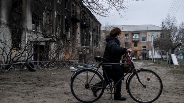 Женщина везет велосипед во дворе жилого дома в городе Счастье в Луганской народной республике