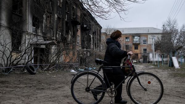 Женщина везет велосипед во дворе жилого дома в городе Счастье в Луганской народной республике