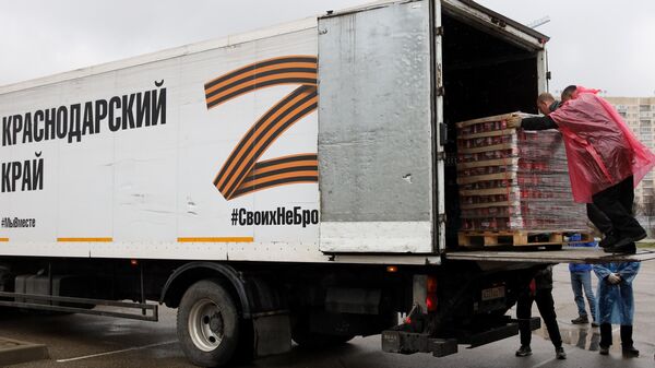 Волонтеры загружают консервированные продукты в грузовые автомобили перед выездом колонны с гуманитарным грузом из Краснодара в Херсон