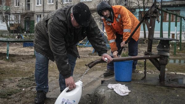 Мужчины набирают воду во дворе жилого дома в городе Счастье в Луганской народной республике