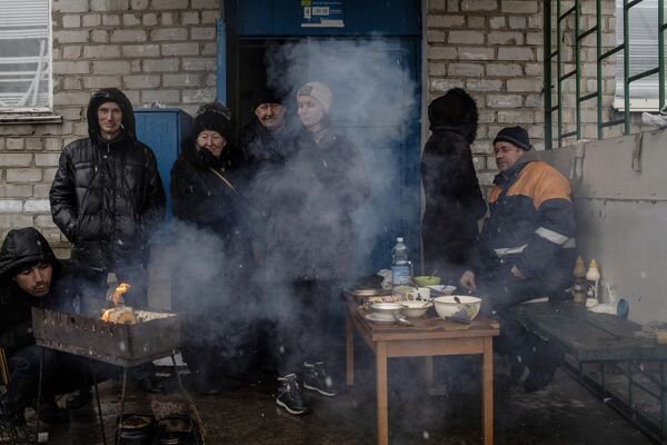 Люди готовят еду у подъезда жилого дома в освобожденном городе Счастье в Луганской народной республике