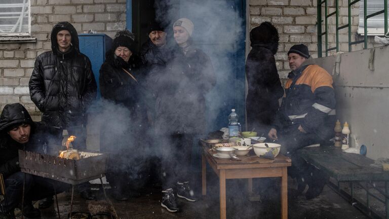 Люди готовят еду у подъезда жилого дома в освобожденном городе Счастье в Луганской народной республике