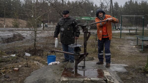 Мужчины набирают питьевую воду в различные емкости во дворе жилого дома в освобожденном городе Счастье в Луганской народной республике