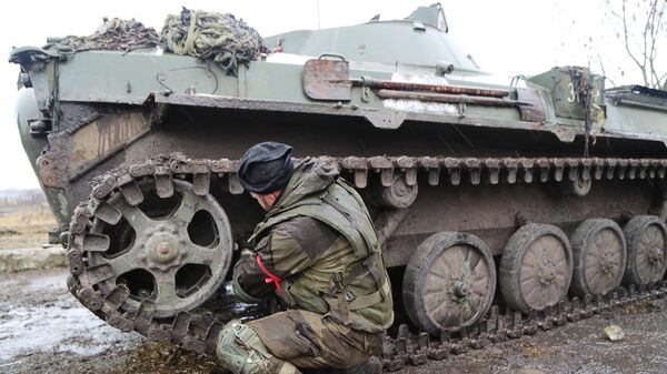 Военнослужащий армии ДНР чинит бронетехнику на дороге в селе Бугас