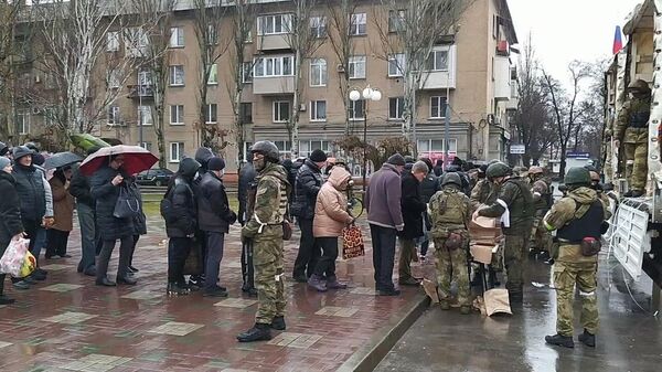 Жители Мелитополя стоят в очереди за получением гуманитарной помощи.