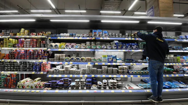 Сотрудник магазина раскладывает товар в гипермаркете