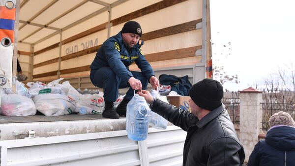 Сотрудник МЧС ДНР передает бутыли воды и продуктовый набор из гуманитарной помощи жителю села Бугас