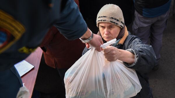 Сотрудник МЧС ДНР передает продуктовый набор из гуманитарной помощи жительнице села Бугас