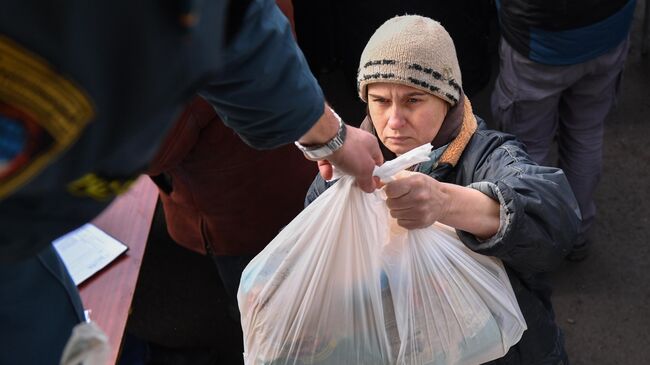 Сотрудник МЧС ДНР передает продуктовый набор из гуманитарной помощи жительнице села Бугас