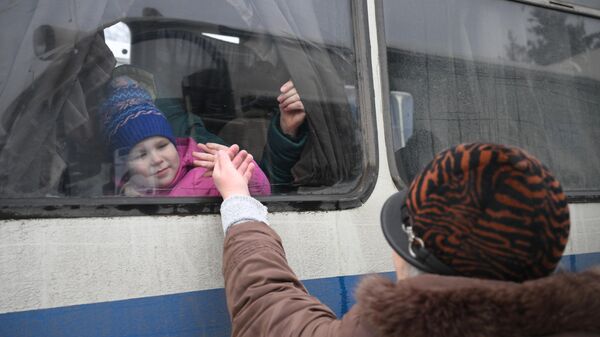 Женщина прощается с ребенком во время эвакуации из Горловки на территорию России