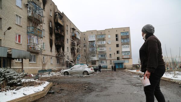 Женщина около жилого дома, поврежденного в результате обстрелов в Донецкой народной республике