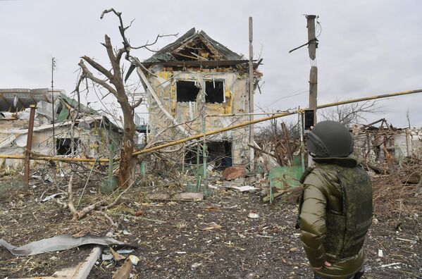 Мужчина фотографирует один из разрушенных домов села Сопино в Донецкой народной республике