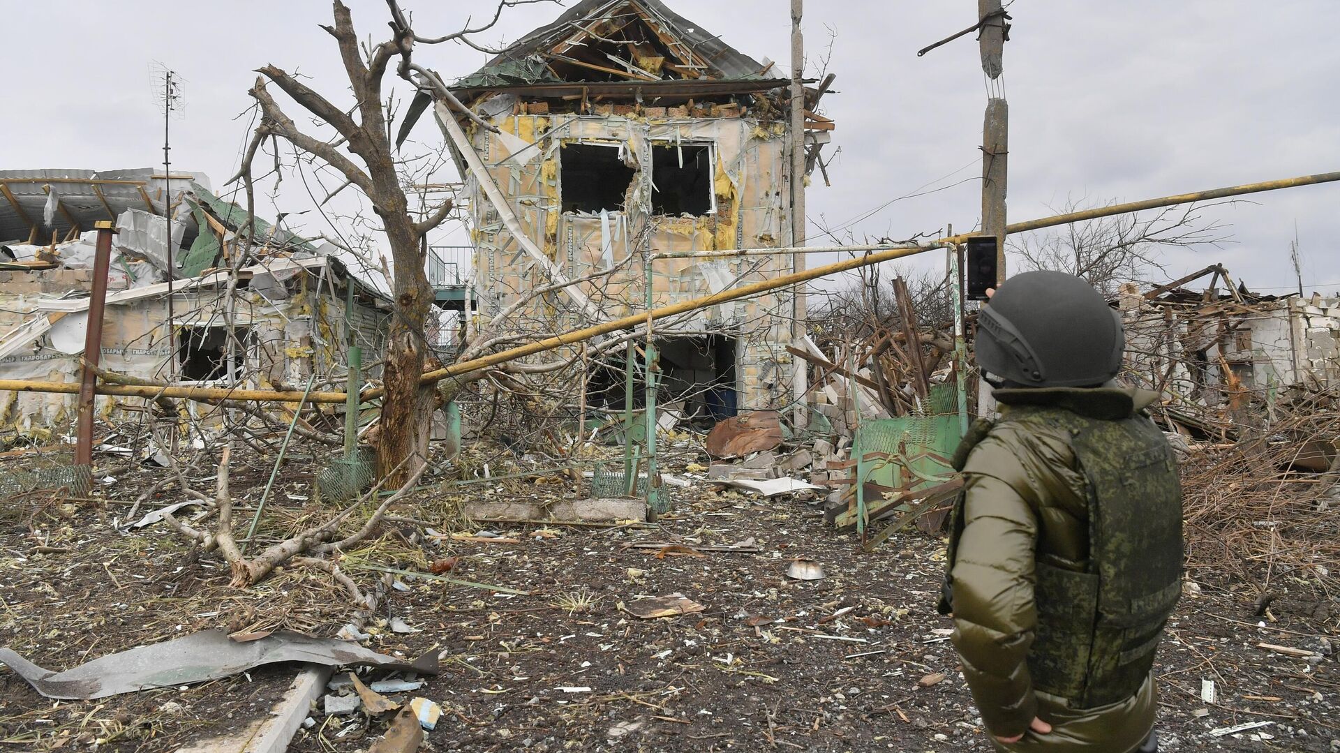 Мужчина фотографирует один из разрушенных домов села Сопино в Донецкой народной республике - РИА Новости, 1920, 12.03.2022