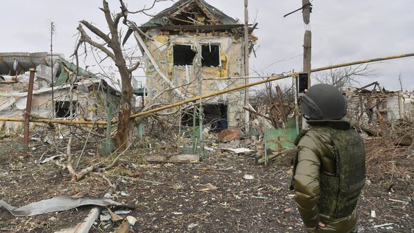 Мужчина фотографирует один из разрушенных домов села Сопино в Донецкой народной республике