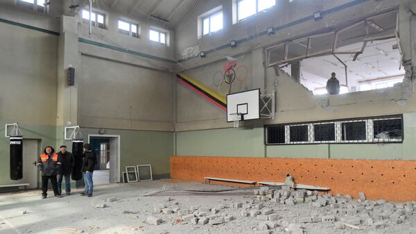 Мужчина в разрушенном спортивном зале специализированной школы с углубленным изучением новогреческого языка в поселке Сартана в Донецкой народной республике