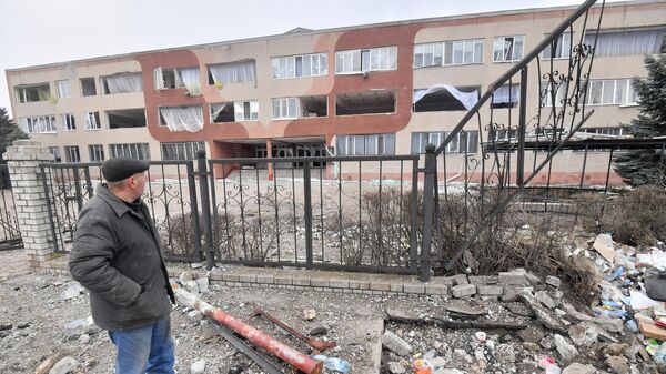 Мужчина у здания специализированной школы с углубленным изучением новогреческого языка в поселке Сартана в Донецкой народной республике