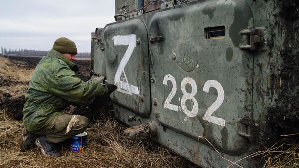 Военнослужащий народной милиции ДНР наносит знак Z на бронетехнику