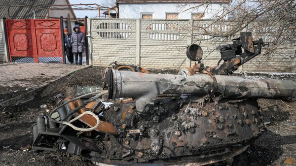 Жители села Новотроицкое Волновахского района смотрят на фрагмент подбитого и сгоревшего танка Вооруженных сил Украины на дороге
