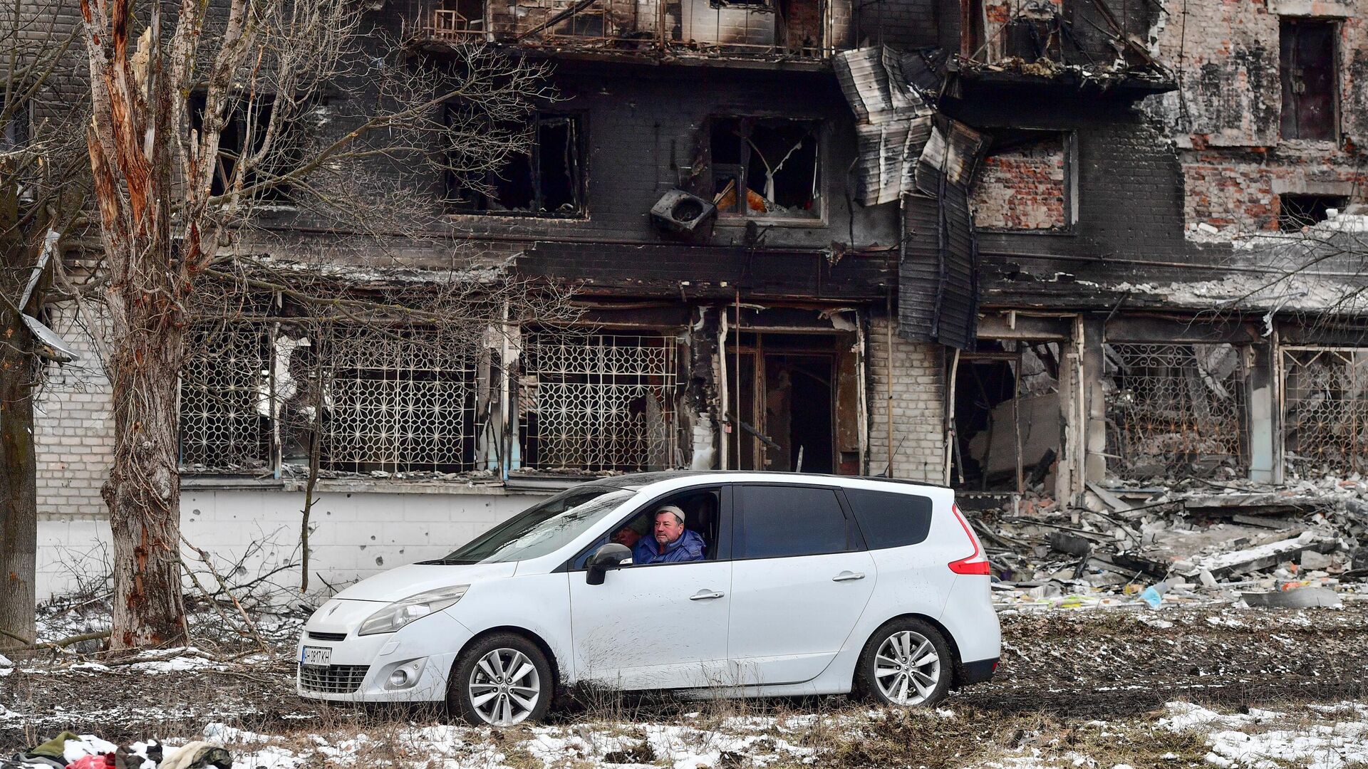 Мужчина едет в машине рядом с домом в Волновахе, разрушенным в ходе боев - РИА Новости, 1920, 12.03.2022