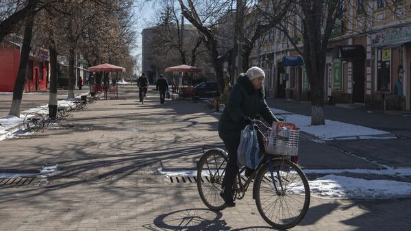 Местная жительница едет на велосипеде на одной из улиц в городе Старобельск
