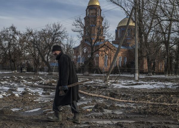 Мужчина несет срубленную ветку дерева в поселке Трехизбенка в Луганской народной республике