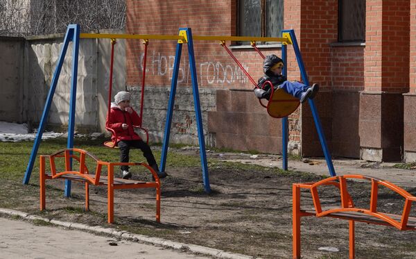 Дети качаются на качелях во дворе жилого дома в станице Луганской в Луганской народной республике