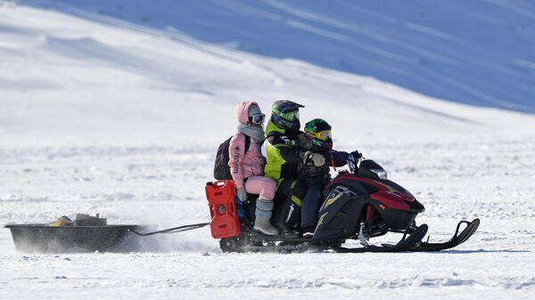 Люди едут на снегоходе по льду Красноярского водохранилища