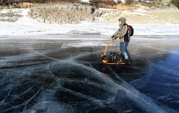 Мужчина едет на электрическом гусеничном самокате по льду Бирюсинского залива 