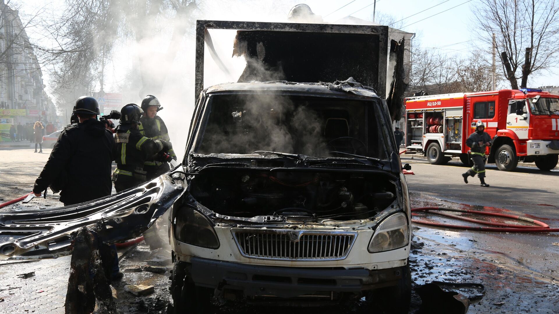 Сотрудники пожарной охраны у сгоревшей машины в результате взрыва в центре Донецка - РИА Новости, 1920, 14.03.2022