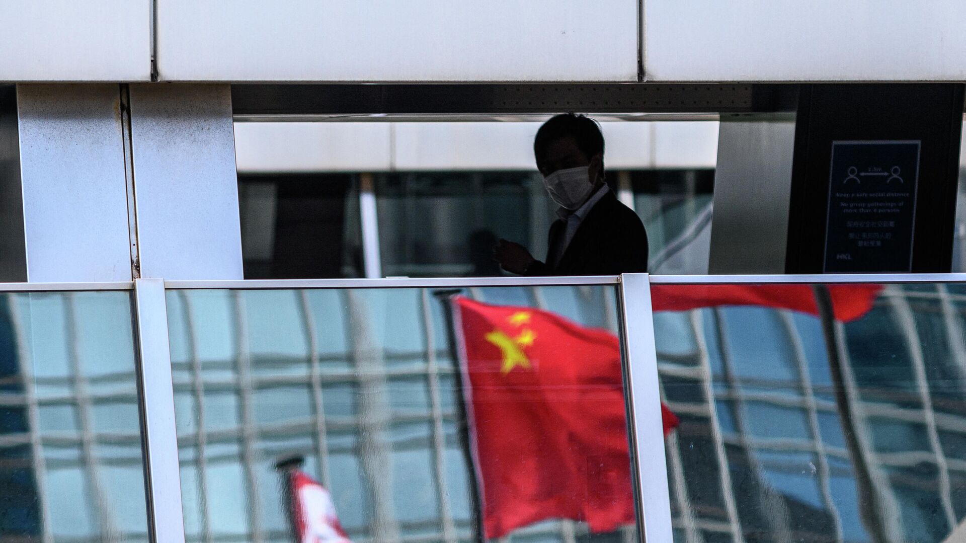 Мужчина проходит мимо отражения флага Китая на пешеходном мосту в Гонконге  - РИА Новости, 1920, 15.03.2022
