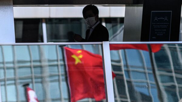 Мужчина проходит мимо отражения флага Китая на пешеходном мосту в Гонконге 