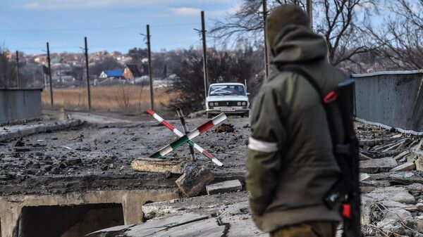 Военнослужащий у разрушенного моста между поселками Сартана и Калиновка в пригородах Мариуполя