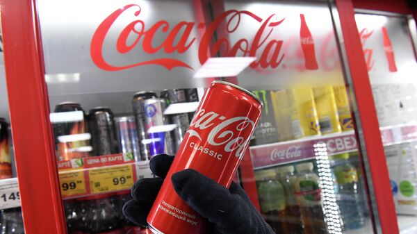 Покупательница берет банку с напитком компании Coca-Cola в продуктовом магазине