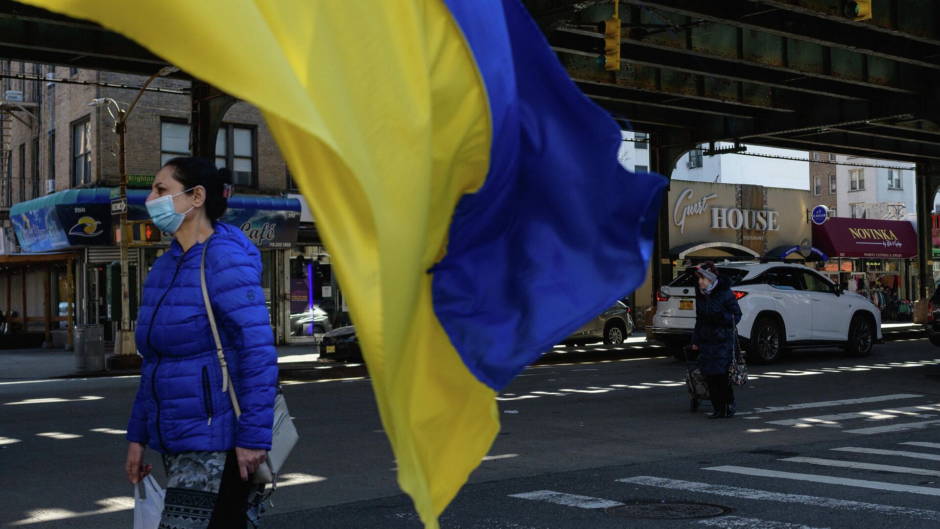 Женщина проходит мимо украинского флага на Брайтон-Бич в Нью-Йорке - РИА Новости, 1920, 17.03.2022