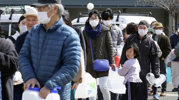 Люди в очереди за водой после сильного землетрясения в Куними, префектура Фукусима, Япония