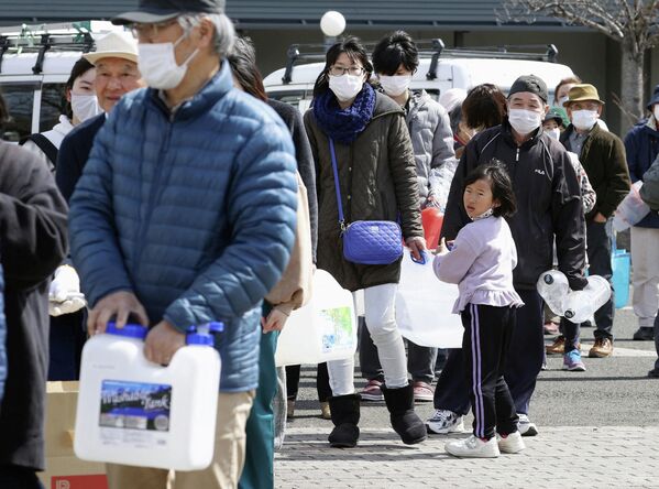 Люди в очереди за водой после сильного землетрясения в Куними, префектура Фукусима, Япония