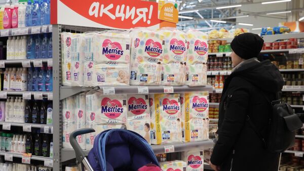 Женщина выбирает детские подгузники в гипермаркете Глобус в Москве