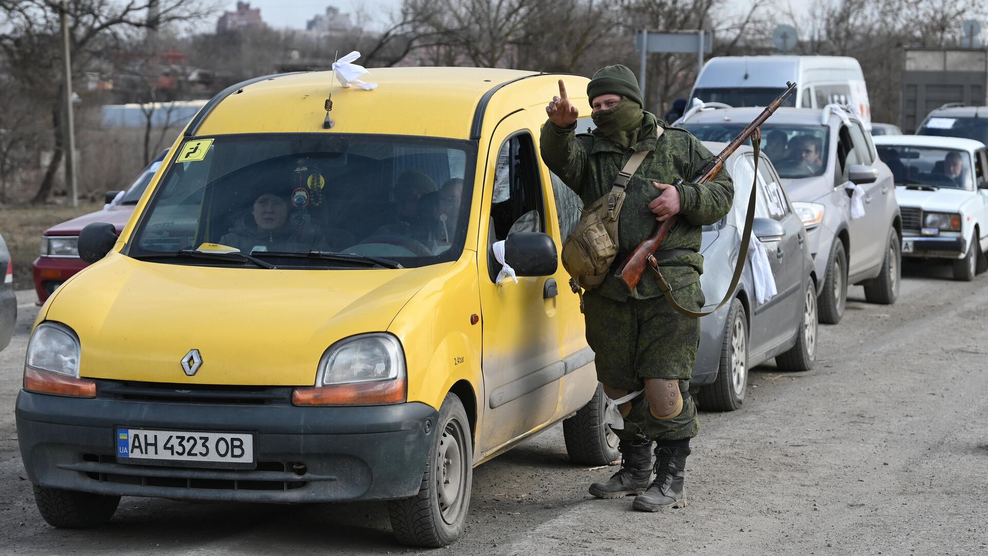 Военнослужащий НА ДНР указывает дорогу беженцам, на автомобиле покидающим Мариуполь - РИА Новости, 1920, 17.03.2022